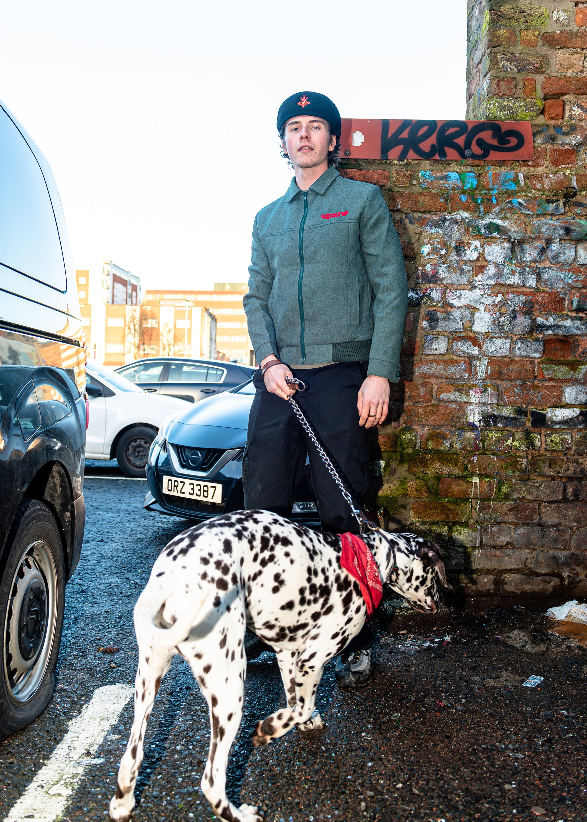 Man wearing Apache Tribe Belfast Mens Zip Jacket in grey with red embroidered logo, styled with black beanie and trousers