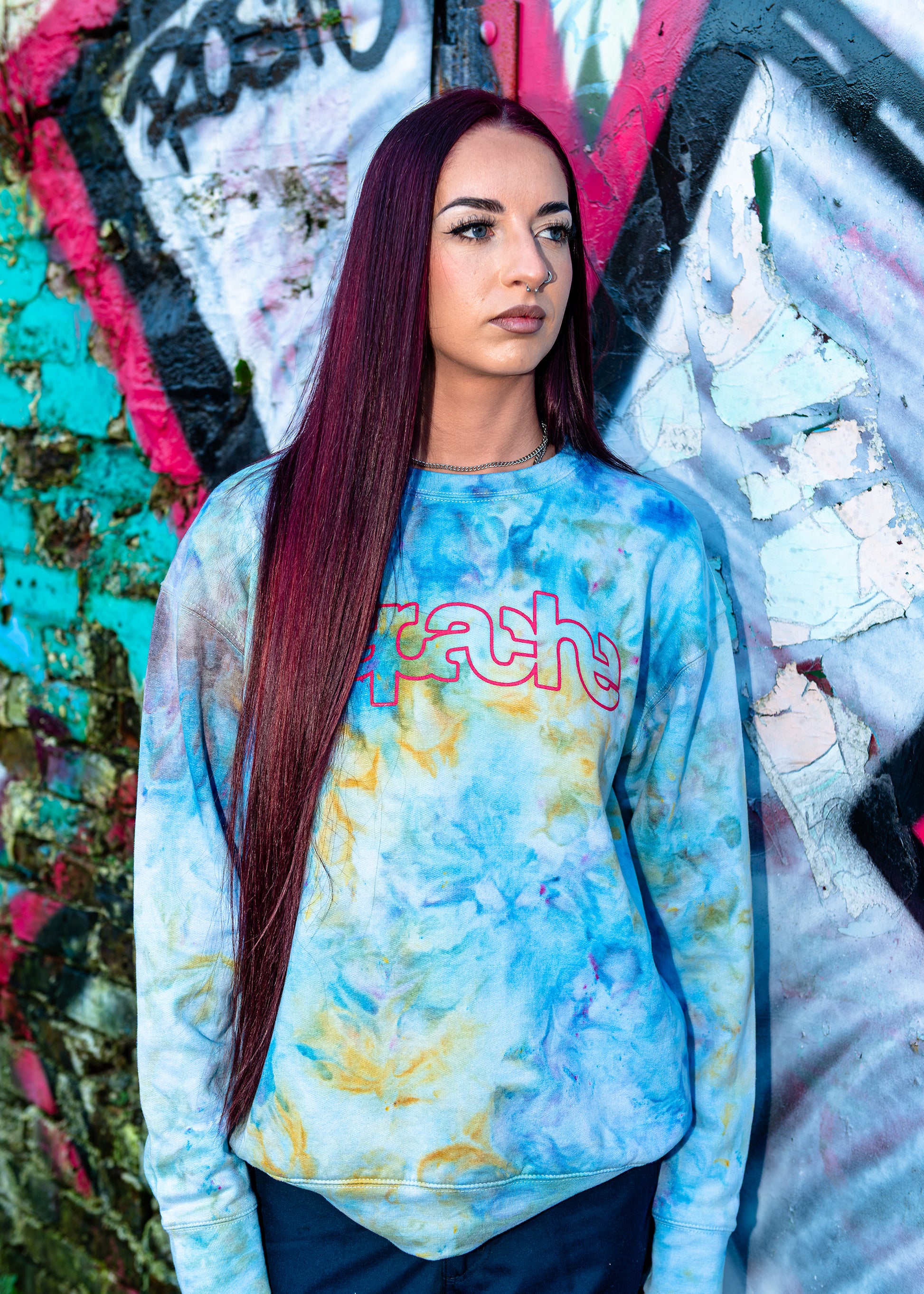 Woman wearing Apache Ice Dye Crewneck sweatshirt in light blue and yellow tie-dye pattern with pink outlined logo on chest