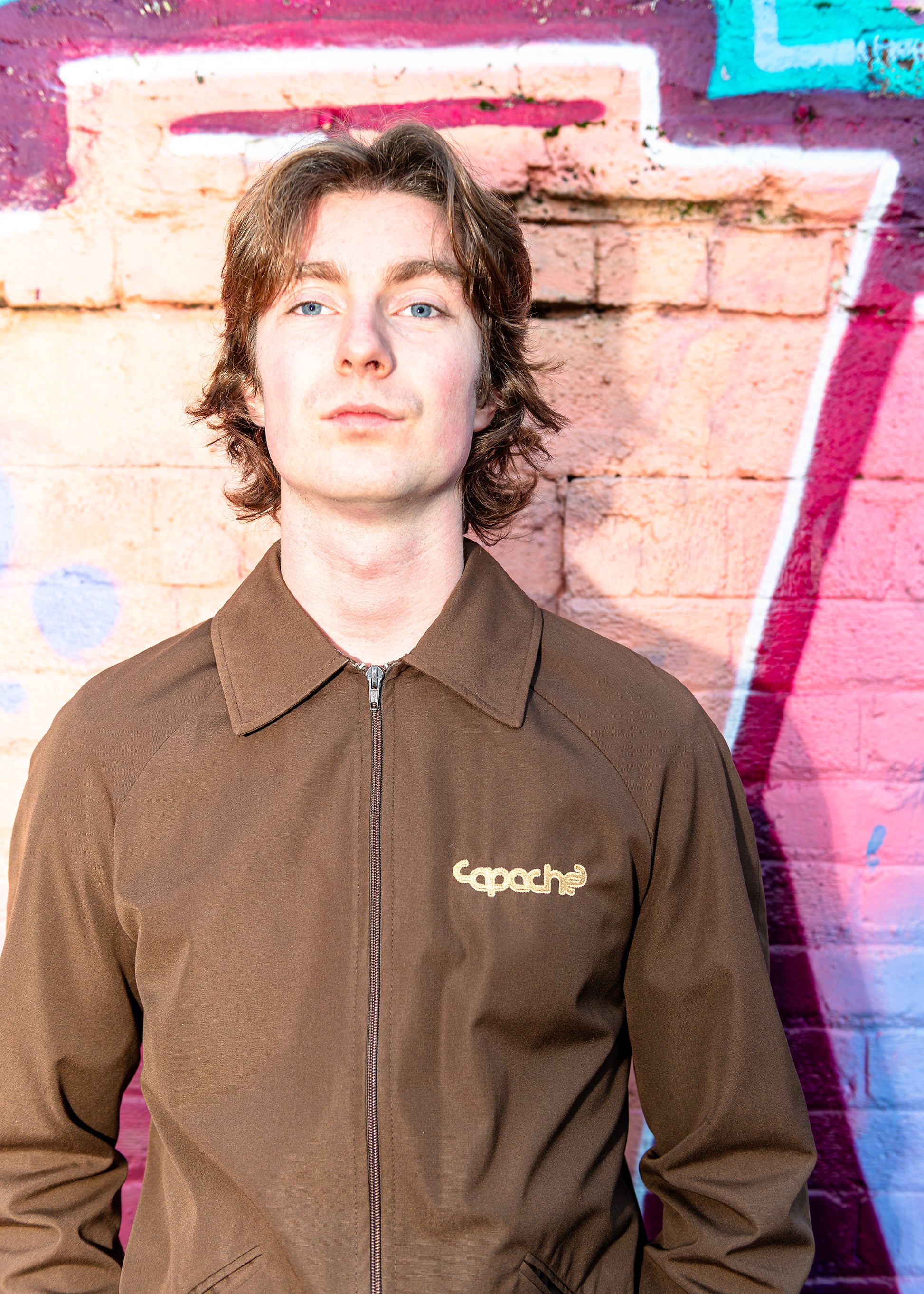 Apache Brown/Gold Zip Jacket featuring brown zip-up collared jacket with gold Capache logo on chest, worn by male model